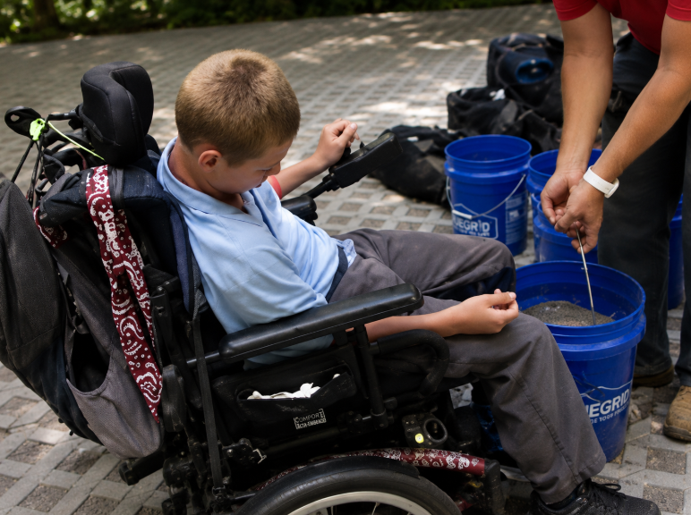 Boy Scout in a wheelchair helping with a TrueGrid paving project.