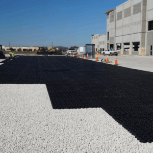 Commercial parking lot installation with black permeable grid panels laid out before filling.