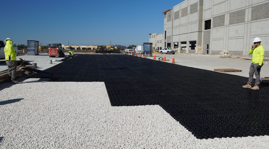 Commercial parking lot installation with black permeable grid panels laid out before filling.