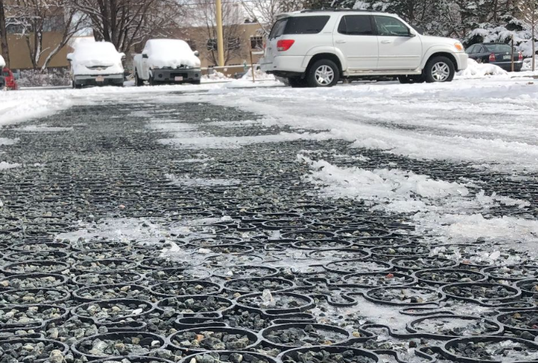 Snow-covered paver driveway with ice buildup and visible joint pattern.