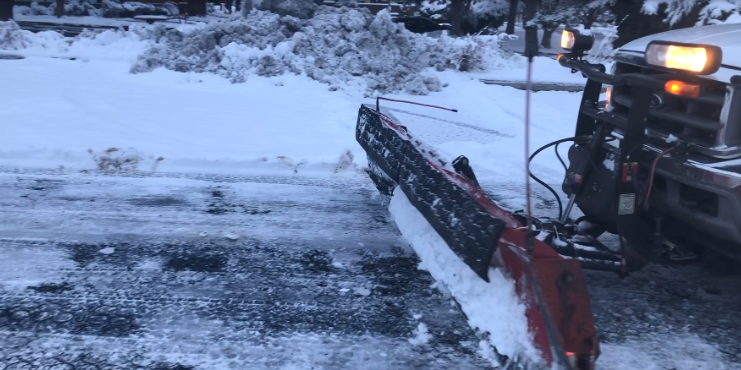 Snowplow clearing a snow-covered permeable driveway in a residential area.