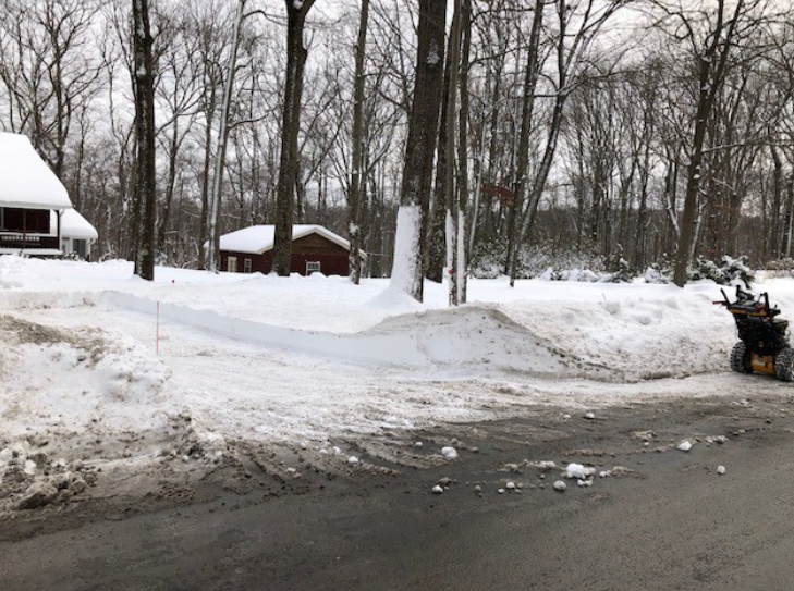 Snowblower has cleared snow on snow-covered permeable driveway in a residential area.