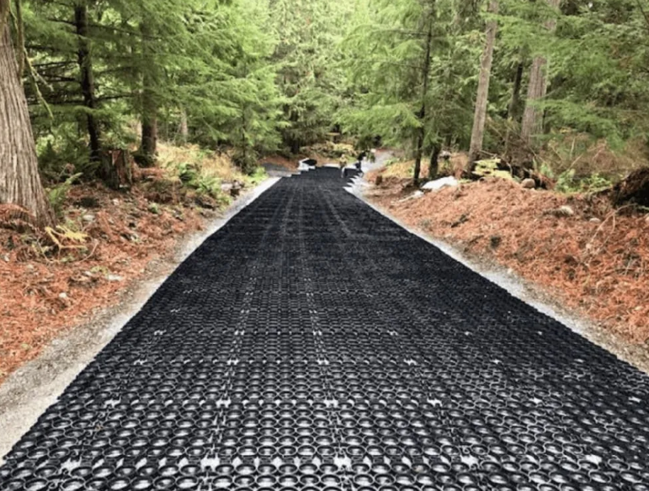Forest road installation using black permeable grid pavers to create a stable and eco-friendly surface.