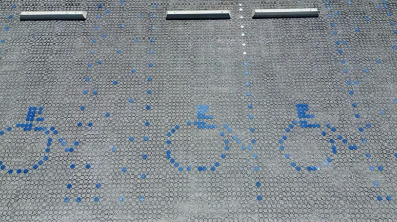 Permeable grid pavers parking bays with blue dots forming accessibility symbol