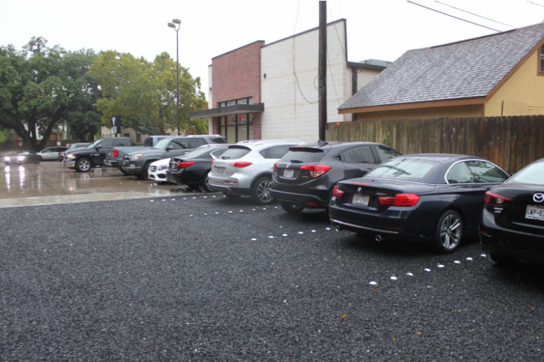 Rain-soaked parking lot with traditional asphalt and permeable sections