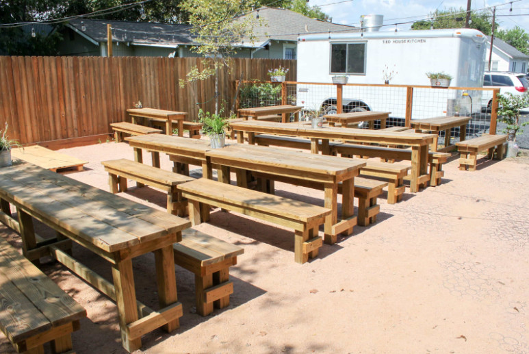 Outdoor dining area with wooden picnic tables and food truck