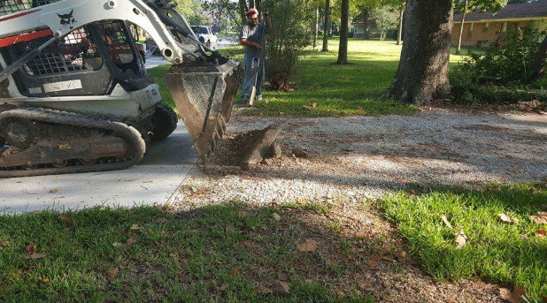A mini excavator removes old materials to make way for a new driveway. 