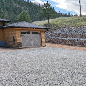 An image of a gravel driveway outside of a small house. 