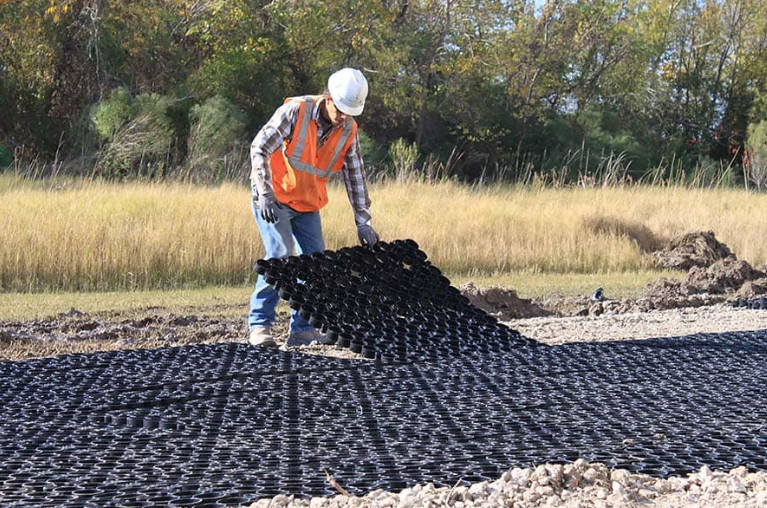 A worker lays down a grid placement to prepare for permeable pavers installation. 