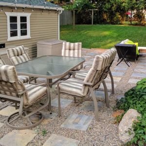 Backyard patio with cushioned seating, gravel and stone pavers, and a grassy yard.