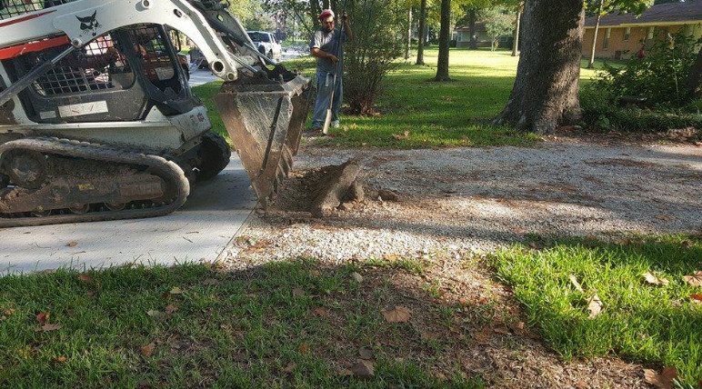 A mini excavator removes old materials to make way for a new driveway. 