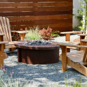 Gravel patio with wooden chairs arranged around a round fire pit.