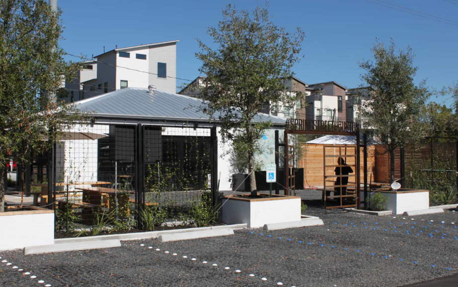 Gravel parking pad in a commercial space with marked spots, trees, and outdoor seating area.