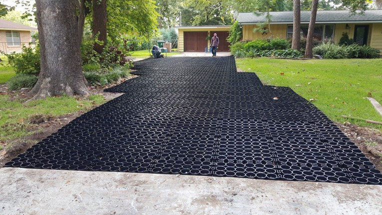 Driveway installation using black permeable plastic pavers for drainage.
