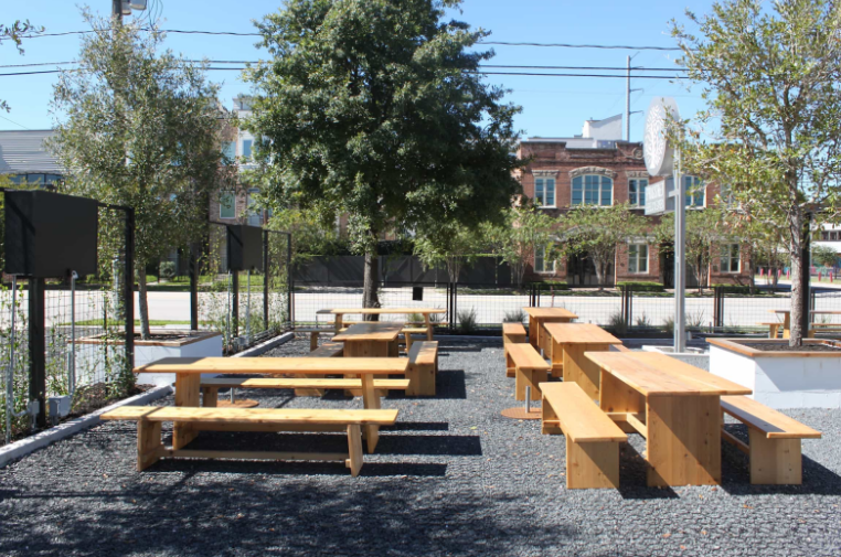 Outdoor picnic tables on a gravel patio surrounded by trees.