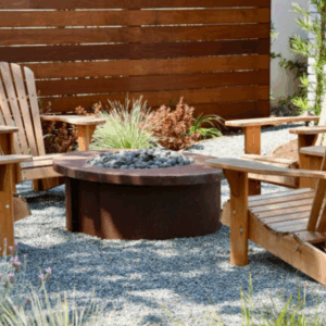 Pea gravel patio with wooden chairs arranged around a modern fire pit.