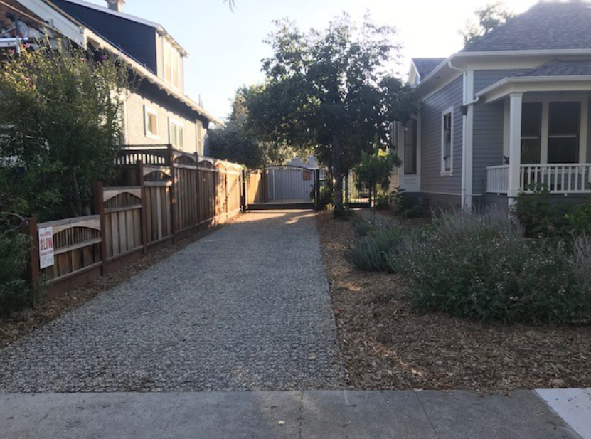 Finished gravel driveway between homes demonstrating affordable paving design.