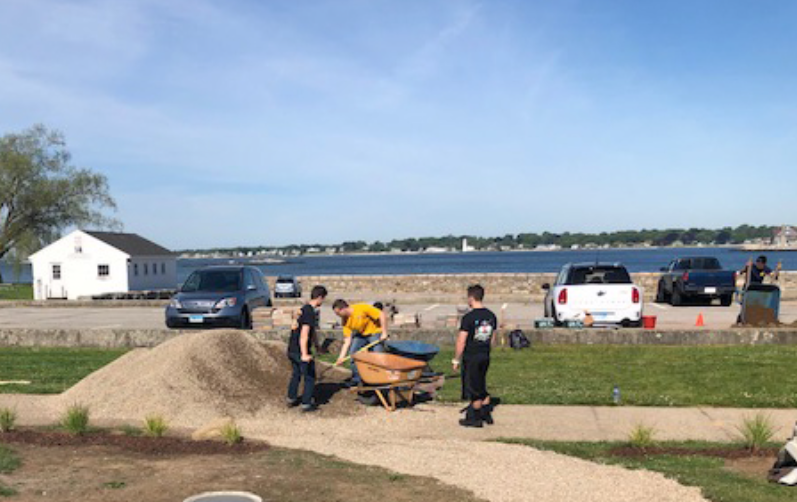 Team transporting gravel for a permeable garden walkway near a waterfront area.