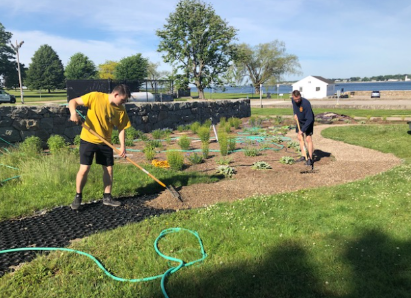Workers spreading gravel over a grid base to create a permeable garden walkway.