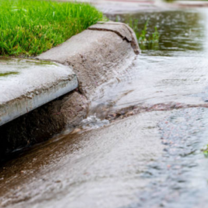 Rainwater flowing along a curb and gutter system as part of home stormwater management.