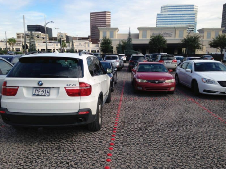 Parking lot with permeable pavers supporting rows of parked vehicles.