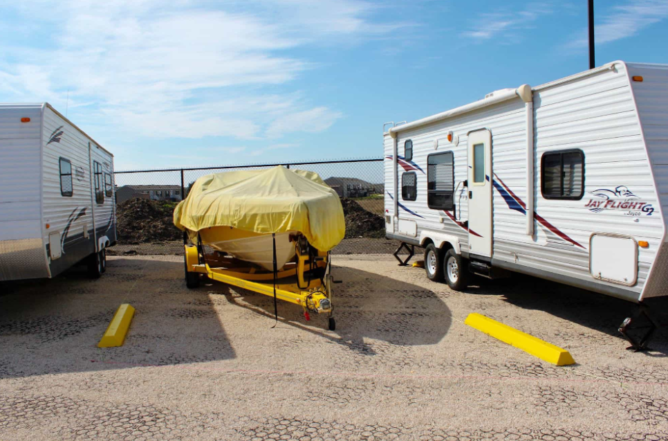 Boat and RV storage spaces with a covered boat parked between two travel trailers.